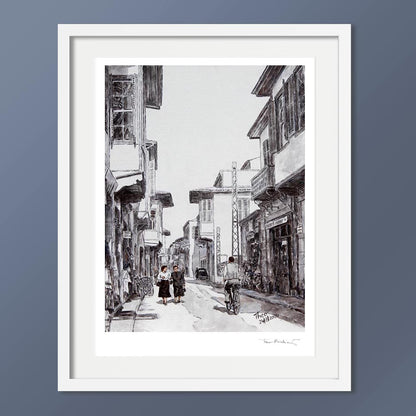 A black and white hand signed fine art print by Theo Michael, depicting Ledra street around the 1950s, featuring traditional buildings, pedestrians and a cyclist.