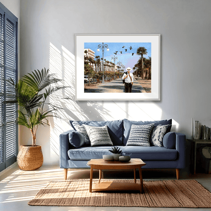 Oil painting of a man walking down a palm tree-lined street with birds flying above, on the seafront promenade in Larnaca Cyprus. An oil painting by Theo Michael.