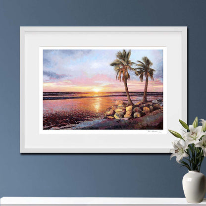 Fine Art print  Sunset by The Sea by Theo Michael, an oil painting featuring a vibrant sunset of orange, pink and yellow, shown in a white frame.